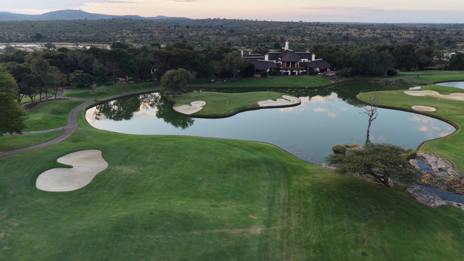 Thatched clubhouse and lake at sunset on a South African golf course