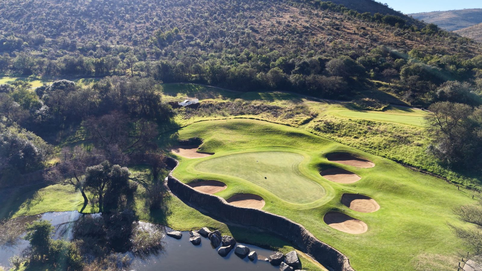 Aerial view of a golf green surrounded by bunkers and river
