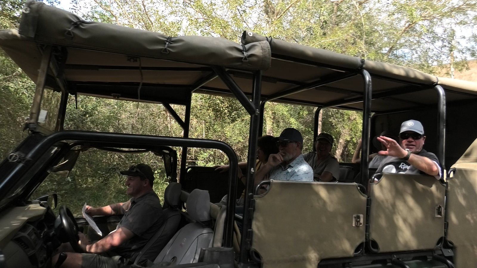 Group waving from an open safari vehicle